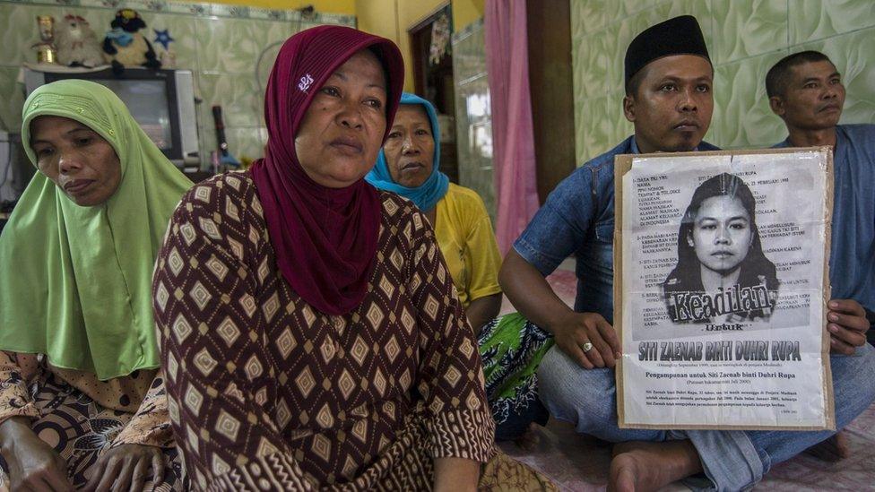 Family members of beheaded Indonesian maid Siti Zainab hold up a poster (R) bearing her portrait at their family home in Bangkalan in East Java province on 15 April 2015