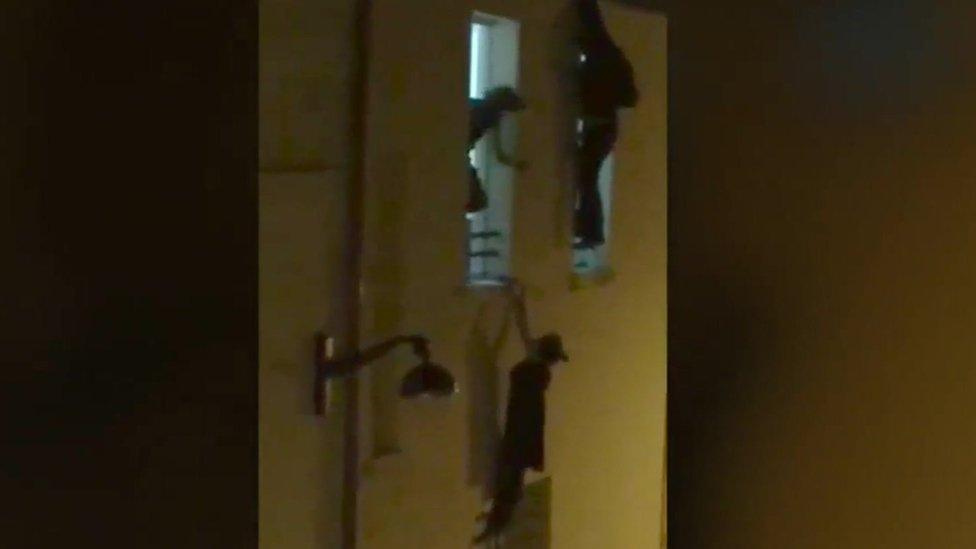 A pregnant woman hangs from a window ledge outside the Bataclan