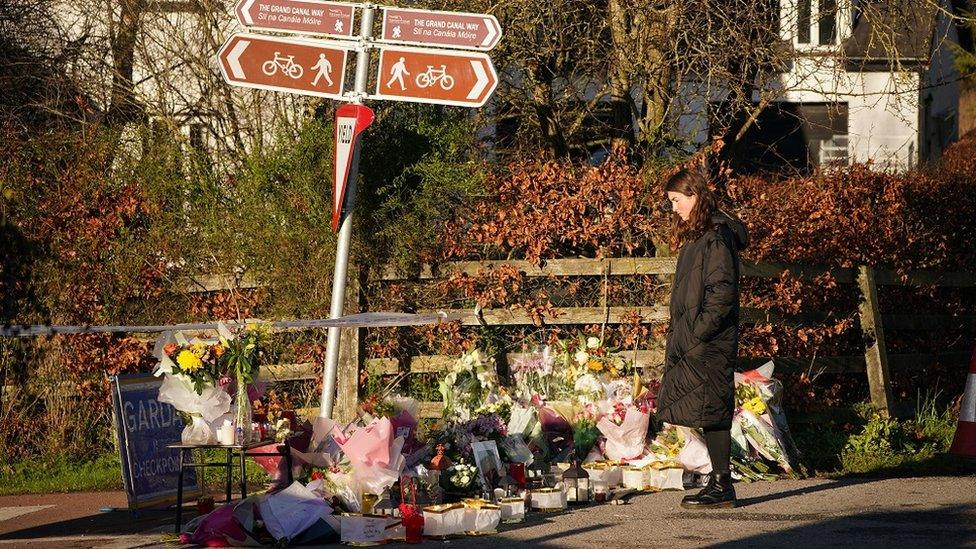 A woman pauses to read messages left on floral tributes laid at the Grand Canal in Tullamore, Co Offaly, where primary school teacher Ashling Murphy was found dead after going for a run on Wednesday afternoon