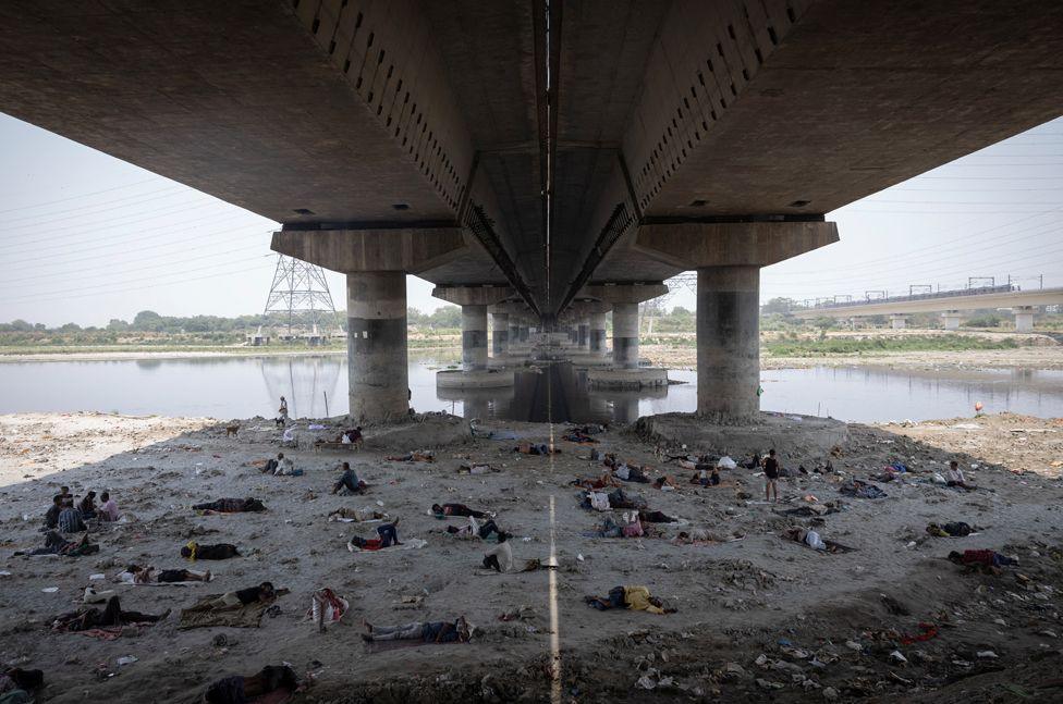 People sleep on the Yamuna riverbed under a bridge on a hot summer day in New Delhi, India, May 22, 2024