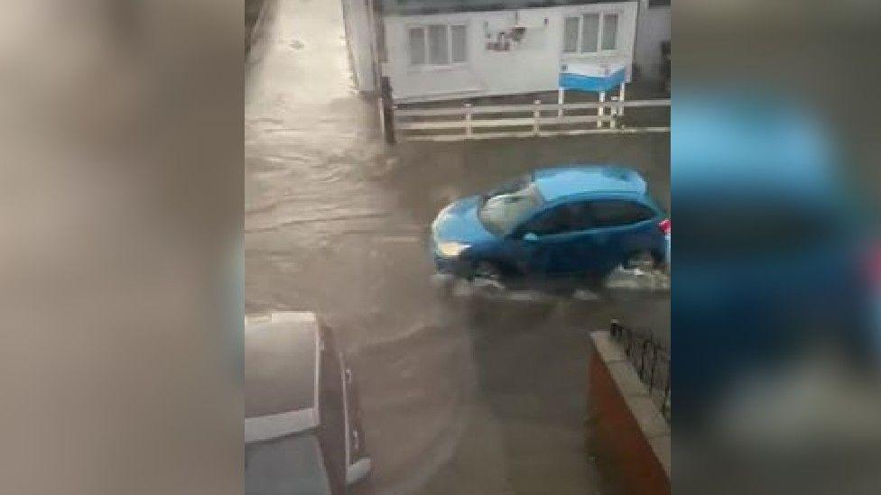 A blue car being driven through deep water 