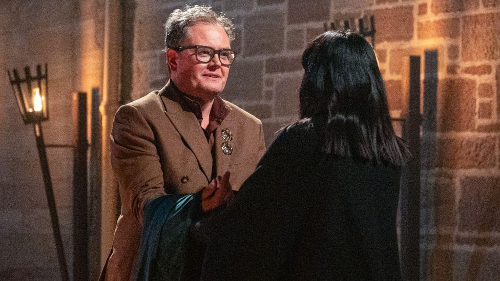Alan Carr receiving his Traitors cloak from Claudia Winkleman
