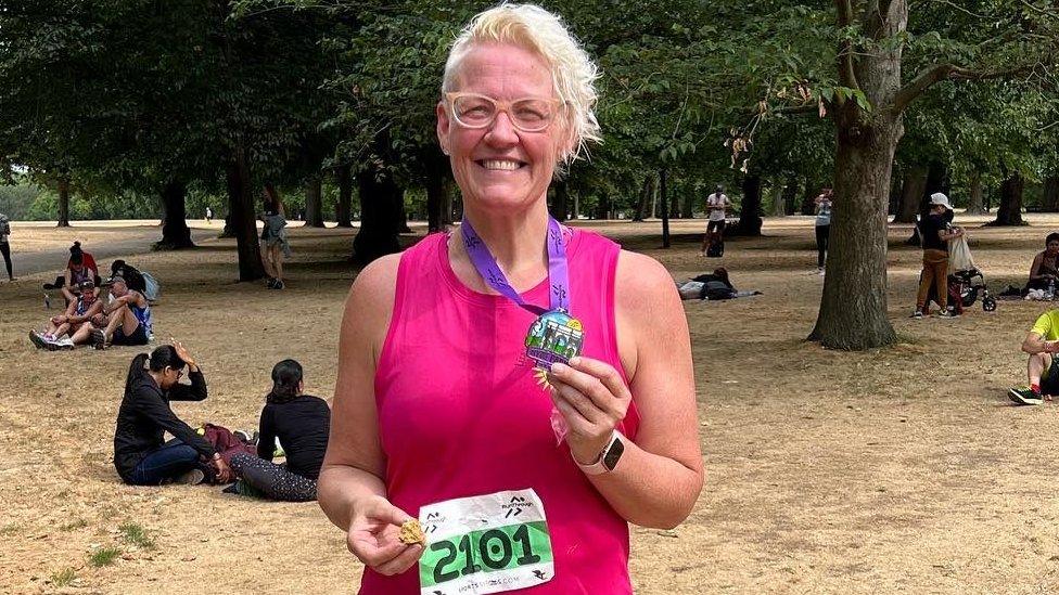 Lisa Cock holding a medal after a 10km run