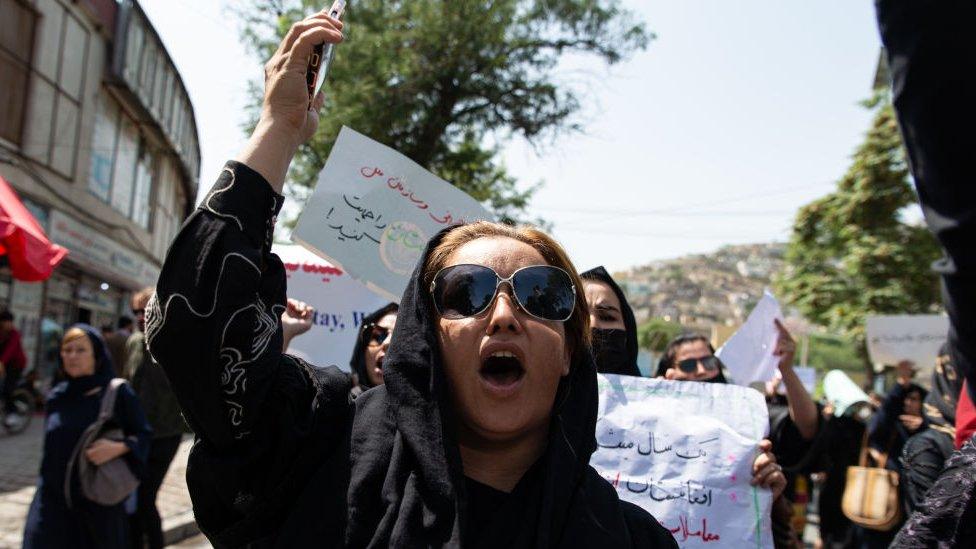 women protesting in kabul holding homemade signs