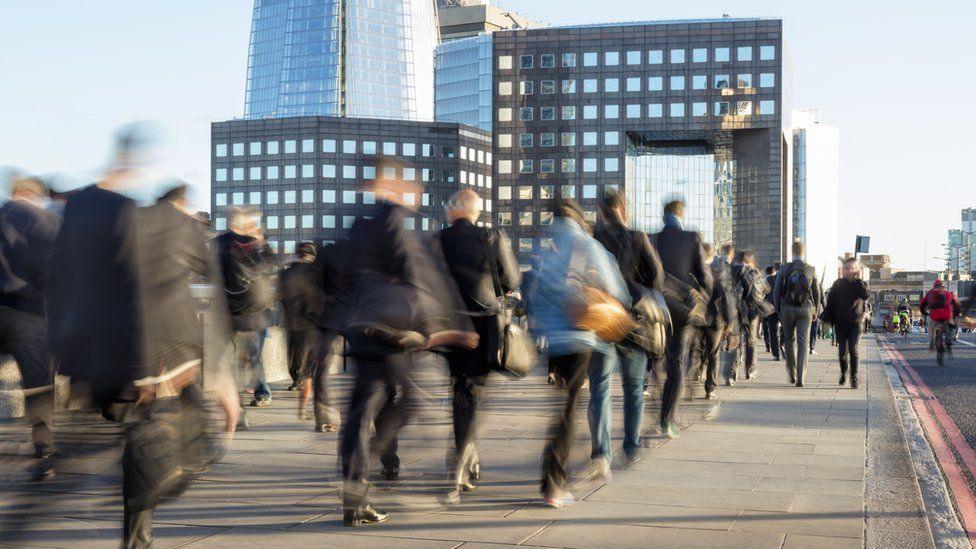 A City of London timelapse photo showing a blurred stream of people walking over a bridge