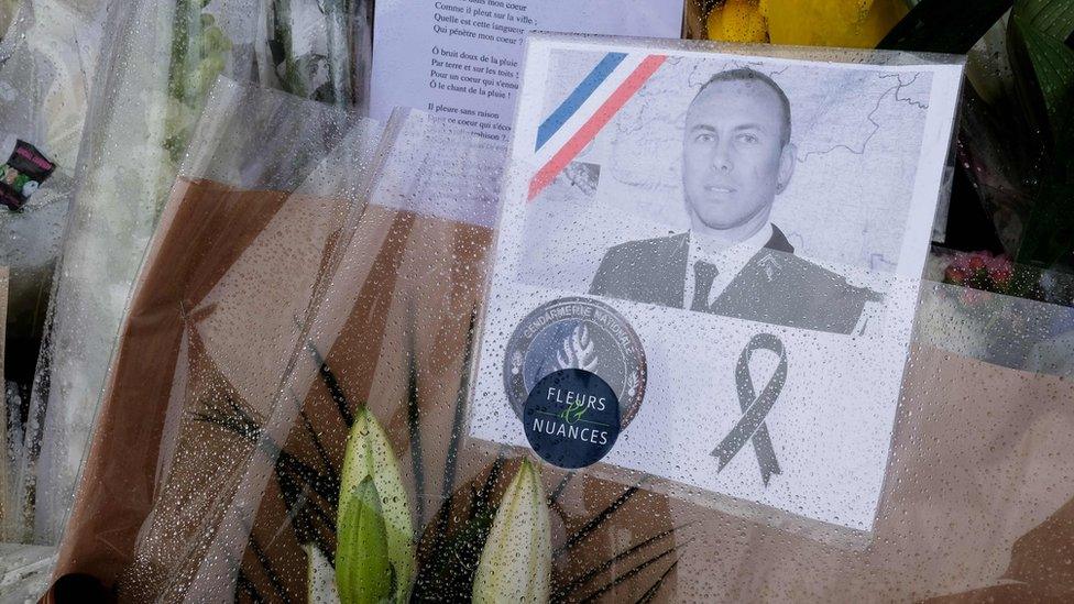 A photo of gendarme Arnaud Beltrame attached to a bouquet in Carcassonne in southwest France on 25 March 2018