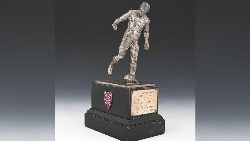 The trophy has a silver statue of Sir Stanley kicking a ball on top of a stand with a bronze plaque saying: "The Footballer of the Year presented to Stanley Matthews by the Football Writers' Association Cup Final eve 1948"