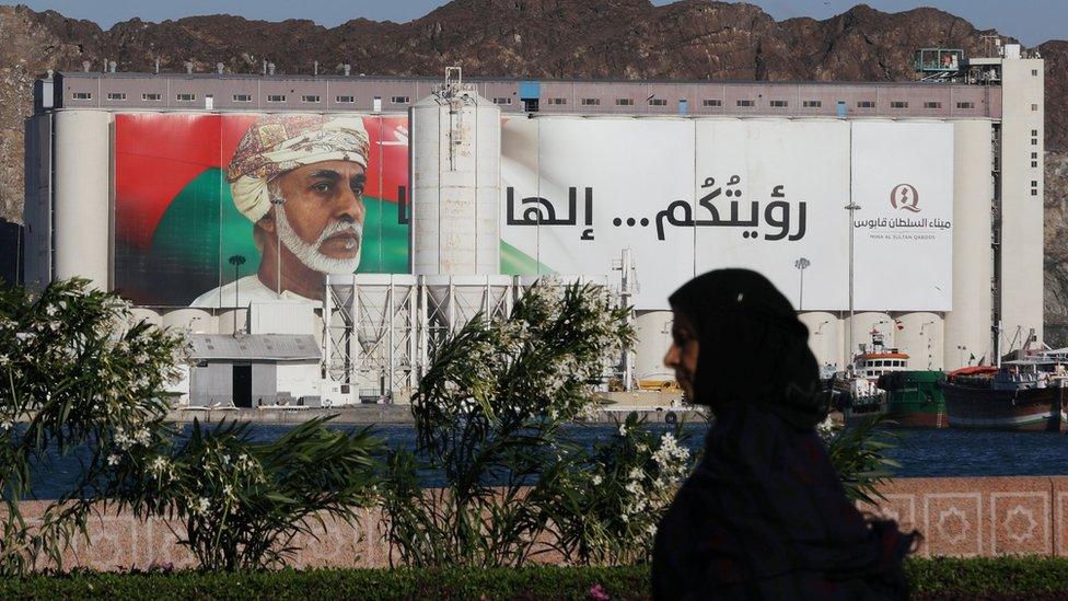 A woman walks past a portrait of Oman's late Sultan Qaboos on a building in Muscat on 12 January 2020