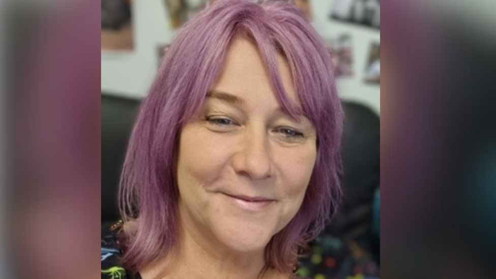 A profile photo of Andrea McCombie, CEO of Ark Trust. She has dyed purple hair and appears to be in her 40s