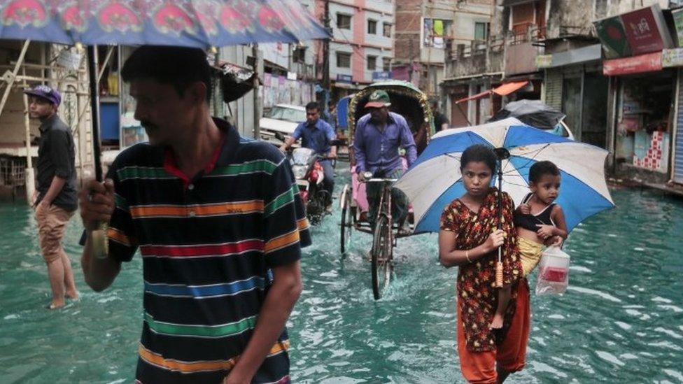 Bangladeshi people walk through waterlogged streets in Bangladesh