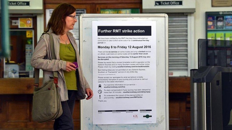 Woman walks past sign about strike