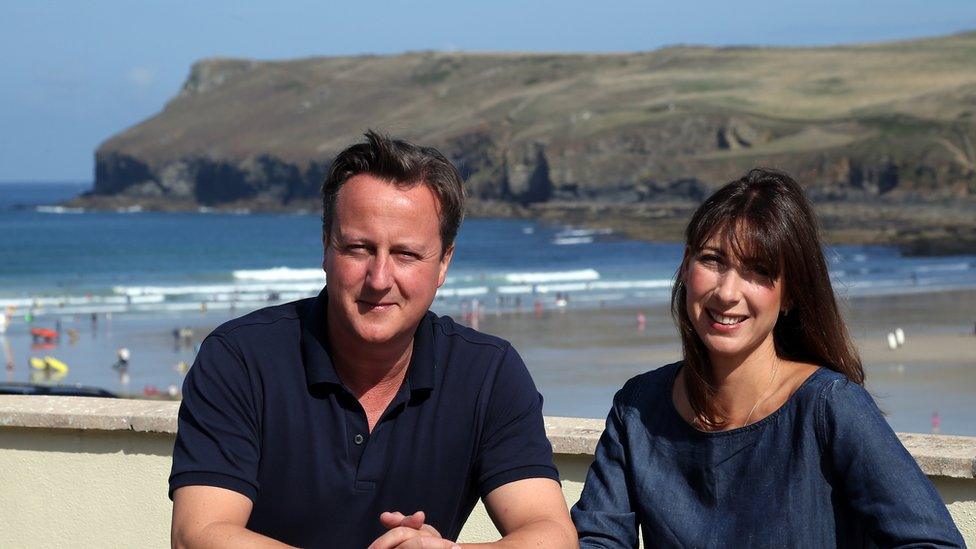 Prime Minister David Cameron and his wife Samantha sit on a bench outside a cafe overlooking the beach at Polzeath