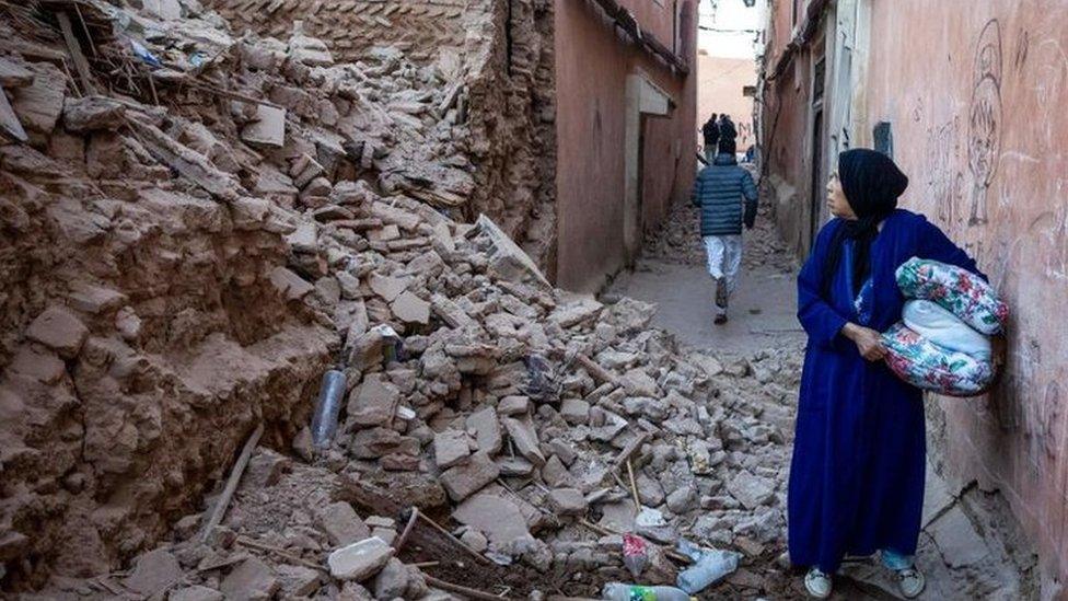 A woman surveys the damage to a building in Marrakesh, reduced almost entirely to rubble