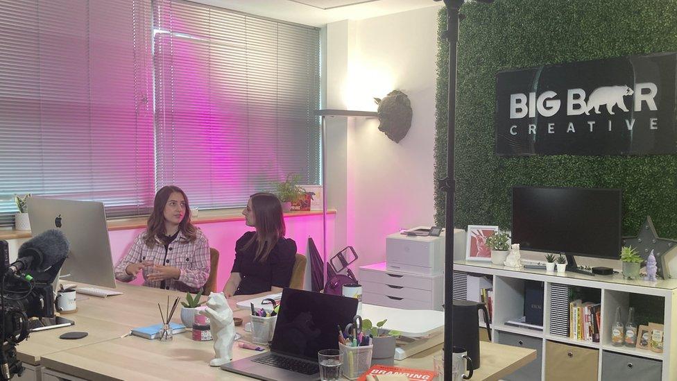 Two women working in an office, sitting in front of a computer screen