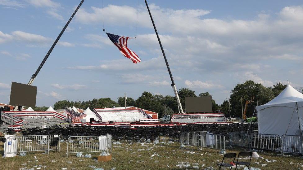 The rally grounds at Butler Farm Show show discarded bottles and debris and an American flag