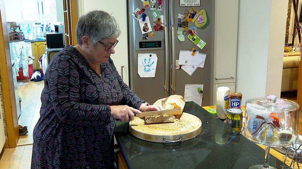 Lynette Petit cutting bread in her kitchen