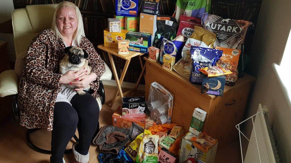 Charlotte Harris holding a dog and surrounded by pet food