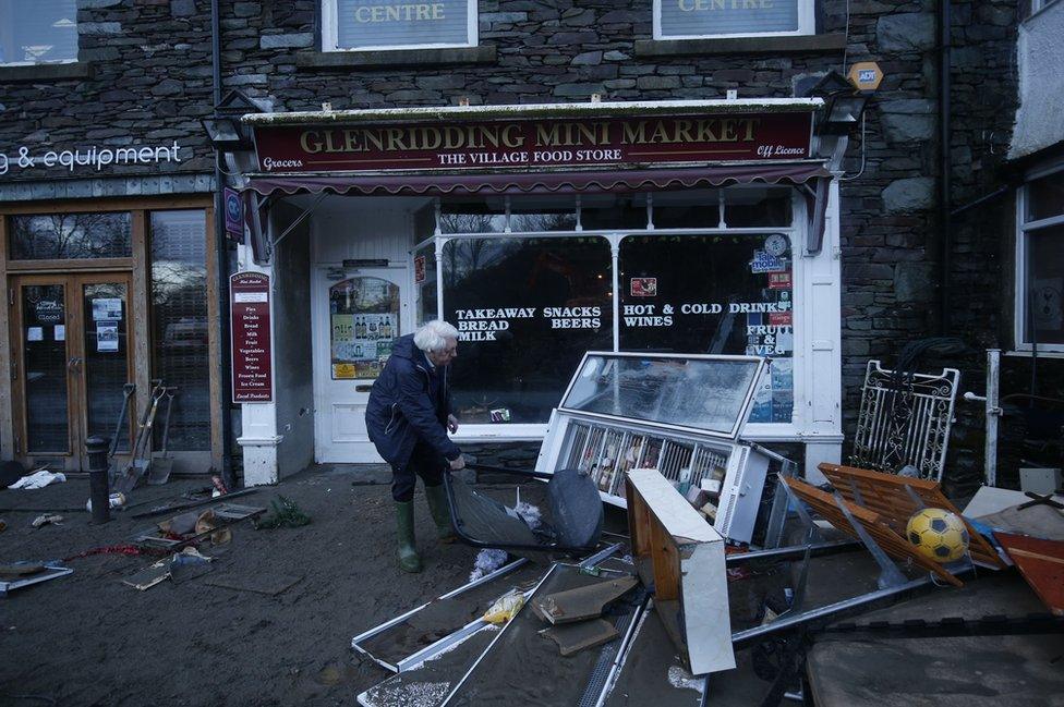 A shopkeeper in Glenridding assesses the damage following the latest flood