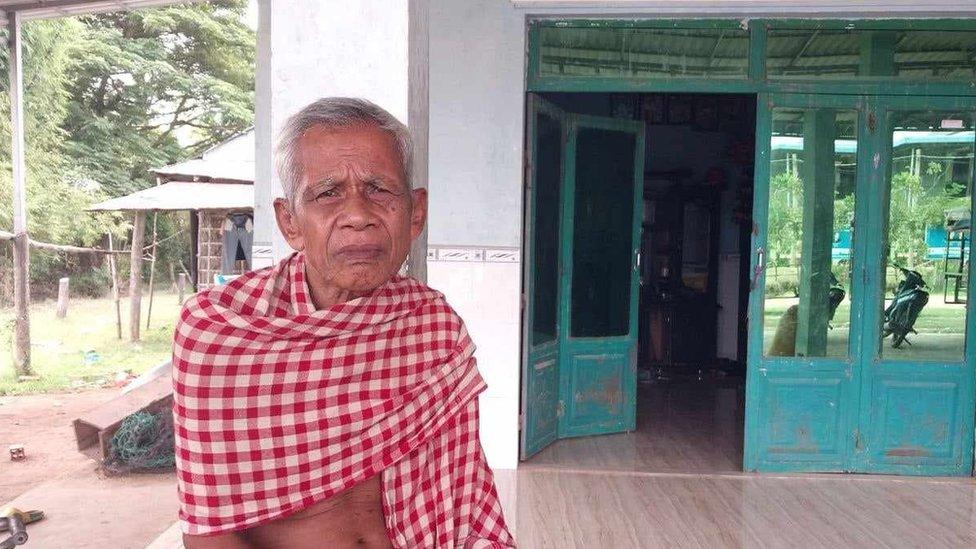 Vorng Chhut sits outside his home in Svay Rieng, Cambodia