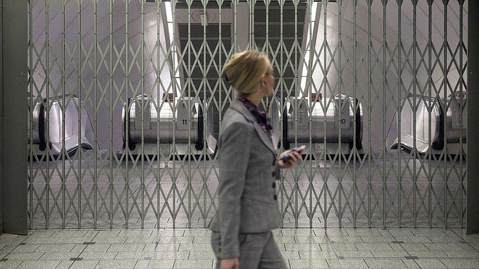 Woman walks past gated station