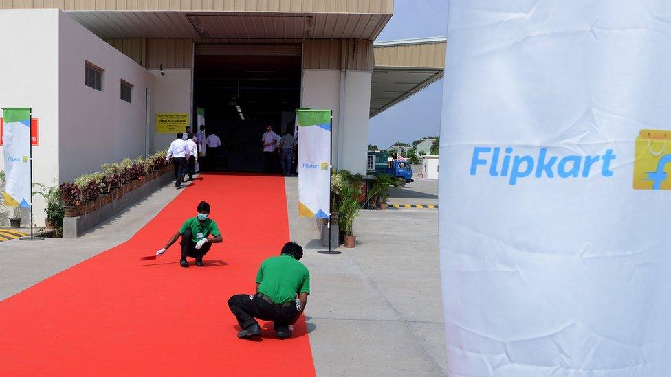 Indian workers clean the red carpet prior to the launch of Flipkart's Largest Fulfillment Centre on the outskirts of Hyderabad on October 30, 2015.