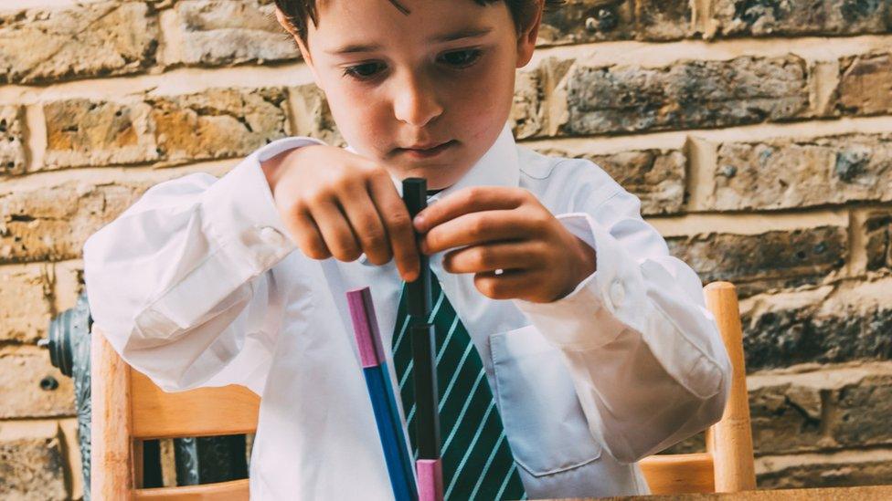 Child building blocks in school uniform