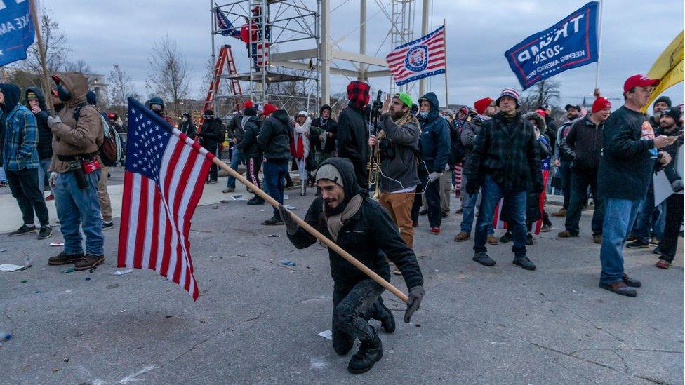 A Trump supporter prays in front of Capitol building where pro-Trump supporters rioted