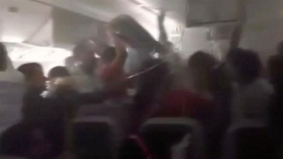 Passengers retrieving hand luggage from burning Emirates airliner