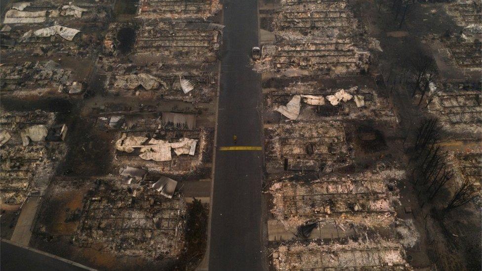 A person walks past gutted homes in the Medford Estates neighborhood in the aftermath of the Almeda fire