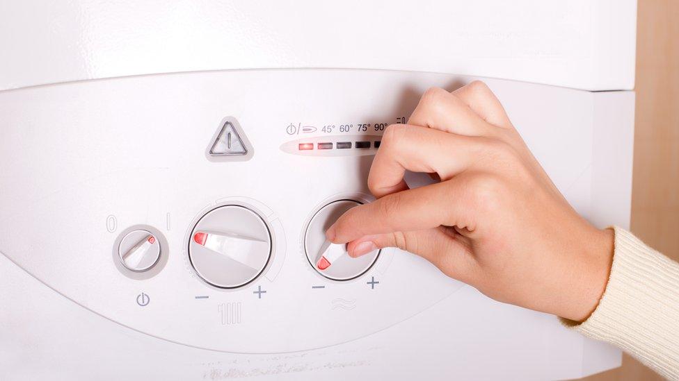 Close up of female hand turning on gas boiler for heating water