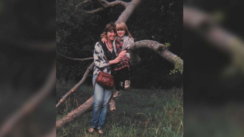 Jacqueline Kirk with her daughter Sonna as a child in front of a tree