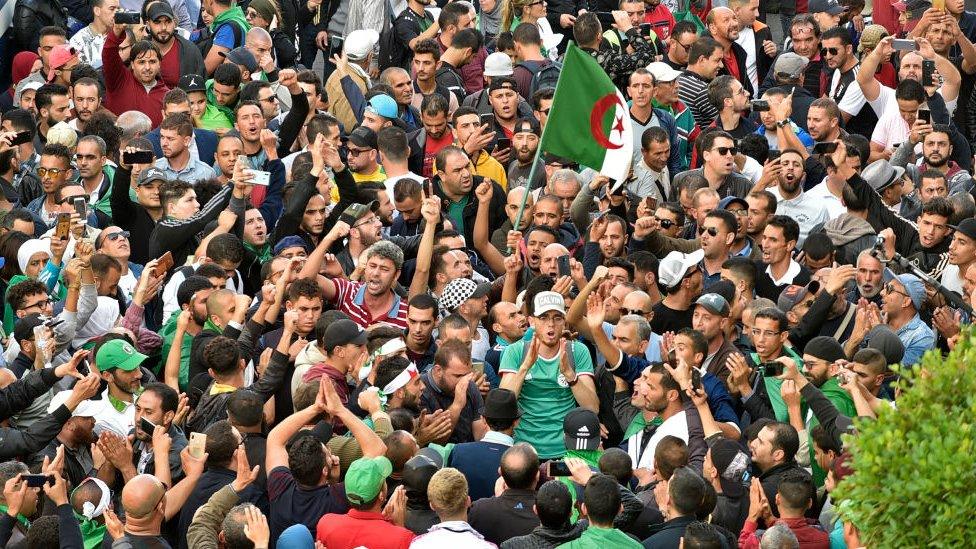 A crowd of protesters shouting and clapping