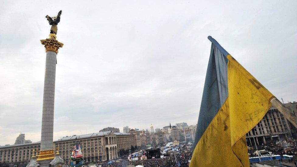 Ukrainian flag flies over Independence Square in central Kiev as people visit memorials to anti-government protesters killed in clashes with police on 23 February 2014