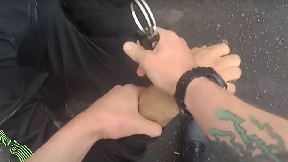 Close-up of police officer putting handcuffs on suspect after a chase