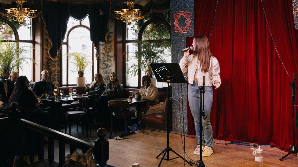 A woman performs solo in a bar.