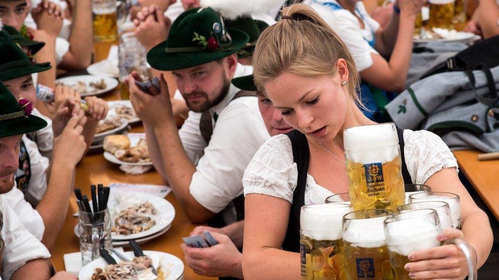 A woman carries several beer mugs in a tent prior to the parade of the traditional Gautrachtenfest in Murnau, Germany, 08 July 2018.