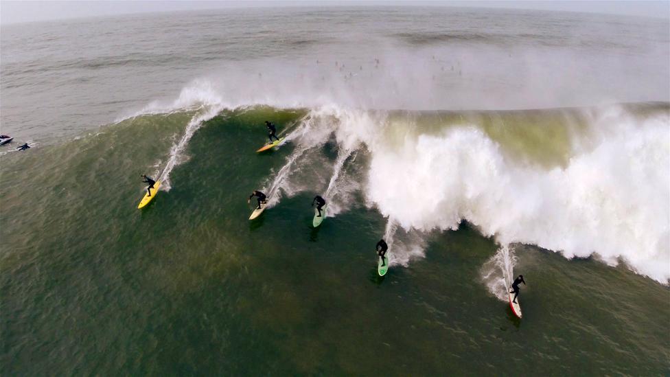 Several surfers riding a really impressive wave