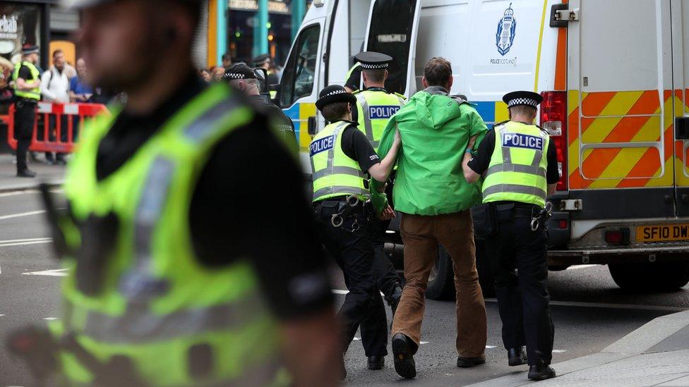 A protester is lead away by police officers on Lothian Road, Edinburgh, during a demonstration by climate change activists