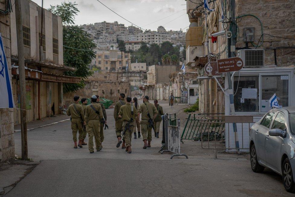 Israeli soldiers walk past Fawaz Qafisha's house. The Palestinian residents are not allowed on the street.