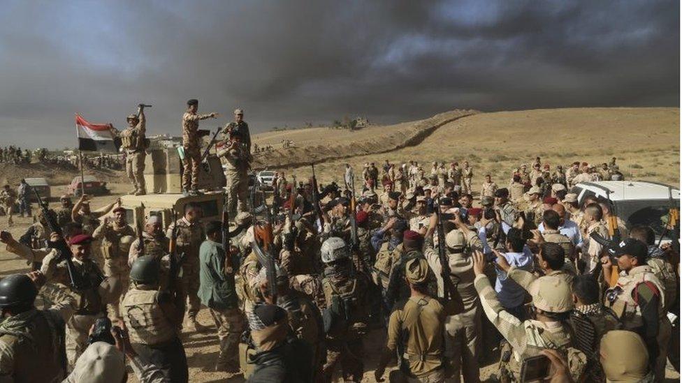 Iraqi army soldiers raise their weapons in celebration on the outskirts of Mosul, Iraq, on 20 October 2016