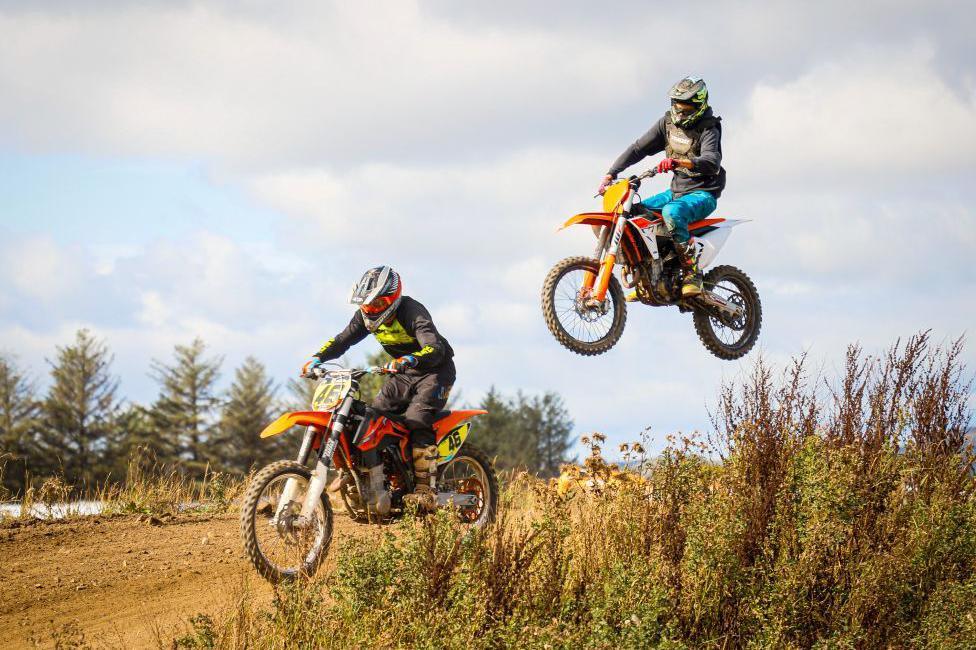 Motocross bikers in action, one leaping in mid air behind another.