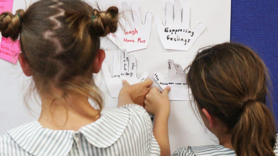 Girls in a drought-affected town stick notes on a whiteboard. Notes read: "Expressing feelings" and "Laugh and have fun"