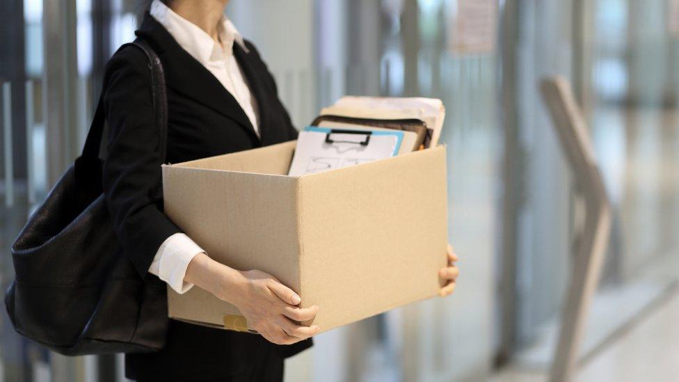 A woman carrying a box out of an office