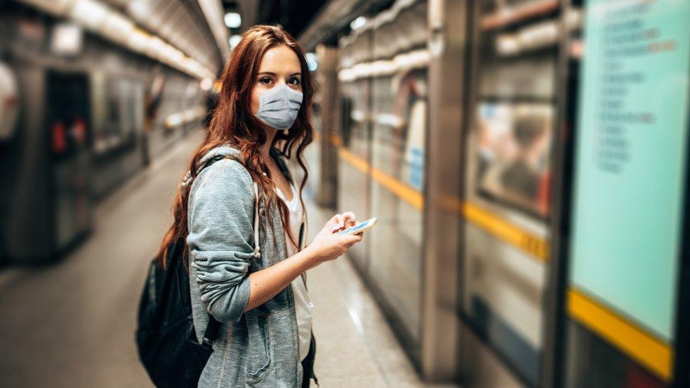 A person in a mask boarding a train