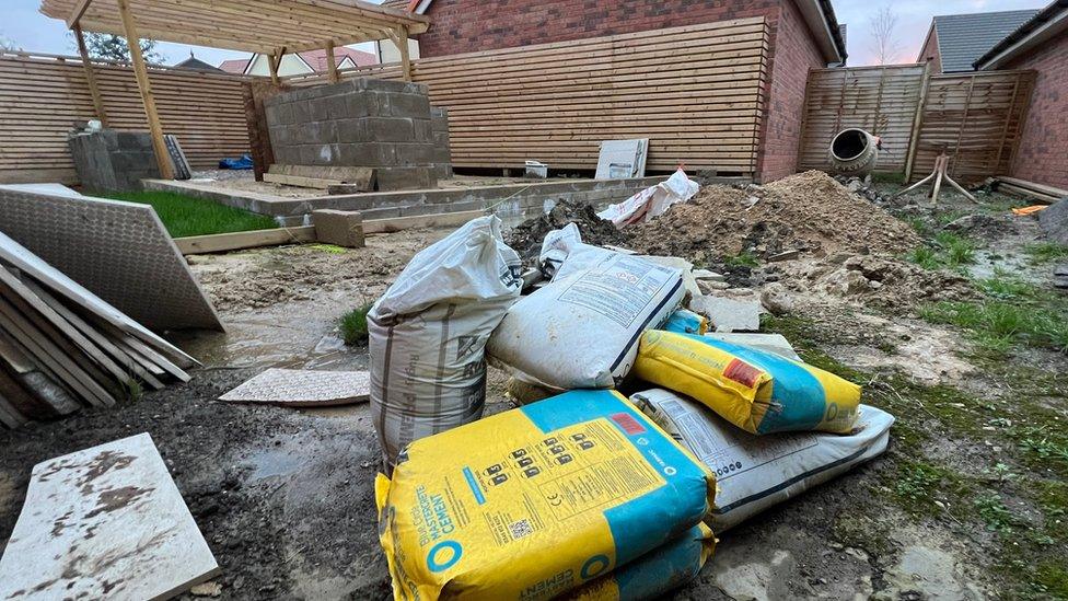 Bags of cement and tiles left in Ms Greenaway's garden and muddy puddles