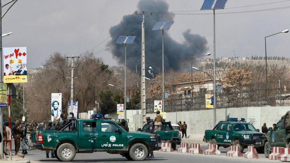 Security forces guard the area as smoke billows from the Sardar Daud Khan Hospital.