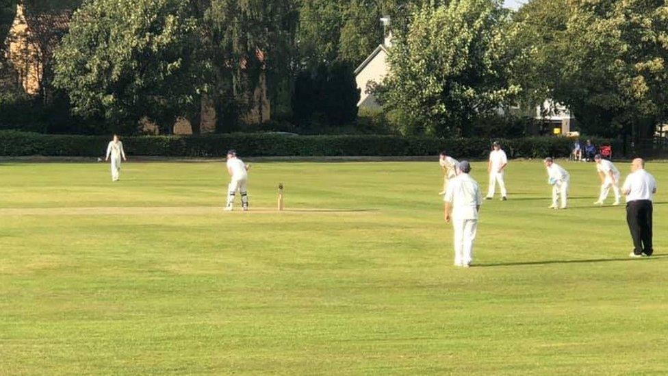 People play cricket on a field