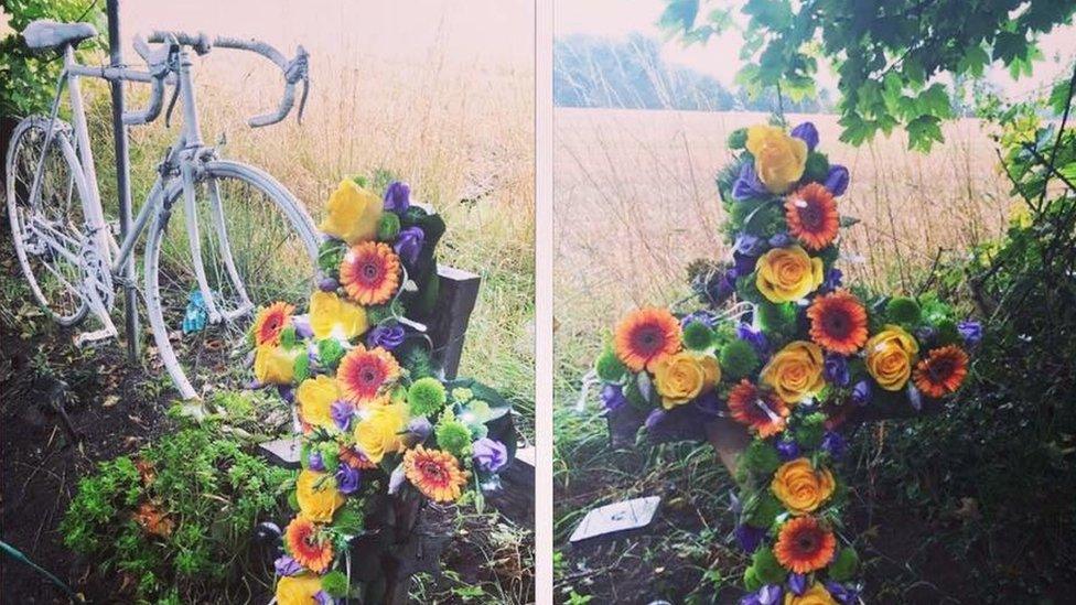 The site where Daniel died showing a white bicycle and cross with flowers on