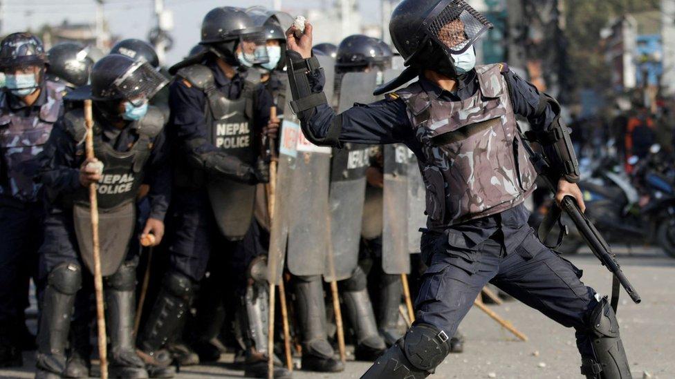 A police officer throws a stone back at protesters