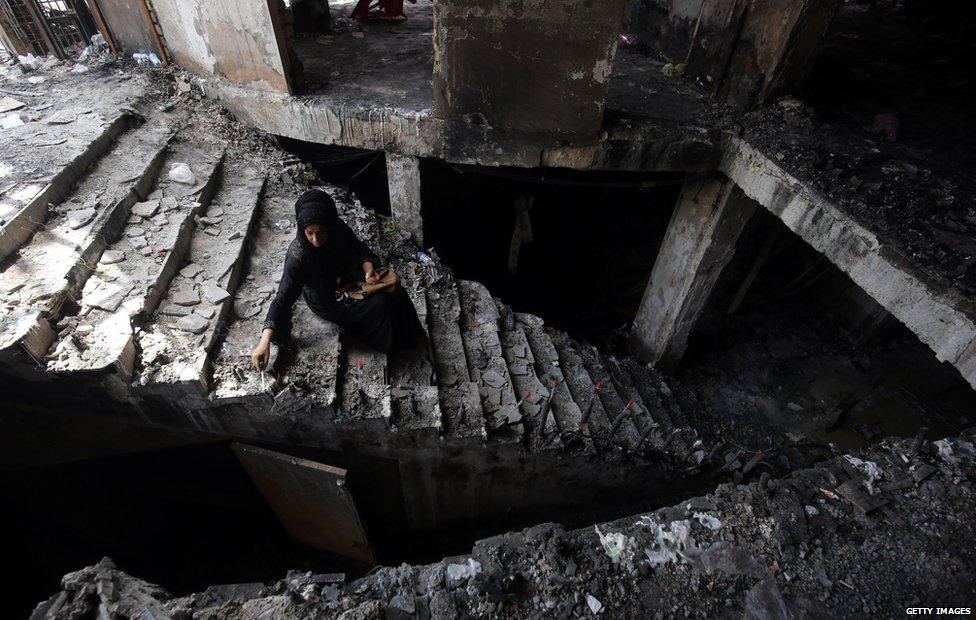 A woman sits in the rubble of a building after a bomb in Iraq claims nearly 300 lives